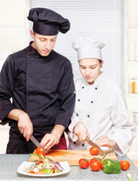 Senior chef teaching young chef to cut. Photo from freedigitalphotos.net